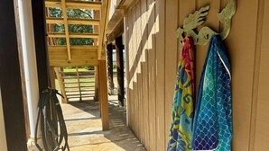 Un intérieur en bois avec un sol en pierre, une échelle en bois et un porte-serviettes mural orné de serviettes colorées.