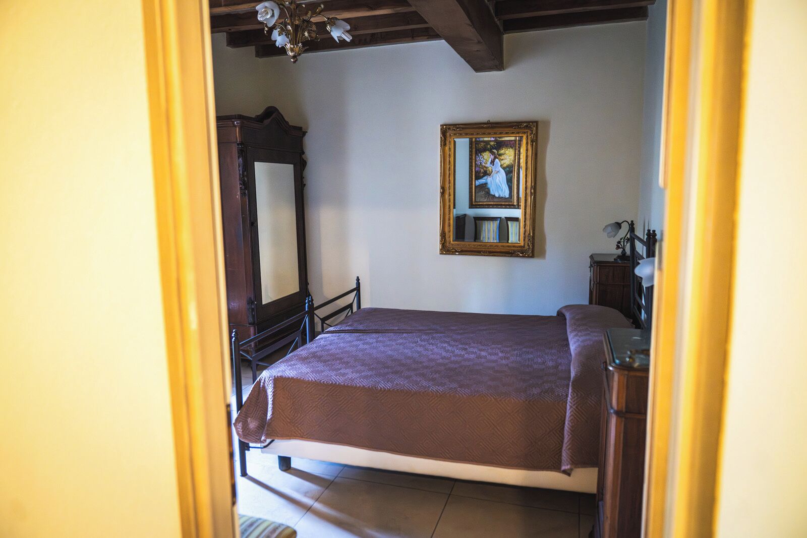 Una habitación con una cama, un aparador de madera, un espejo y un cuadro en la pared.