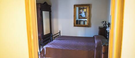 Una habitación con una cama, un aparador de madera, un espejo y un cuadro en la pared.