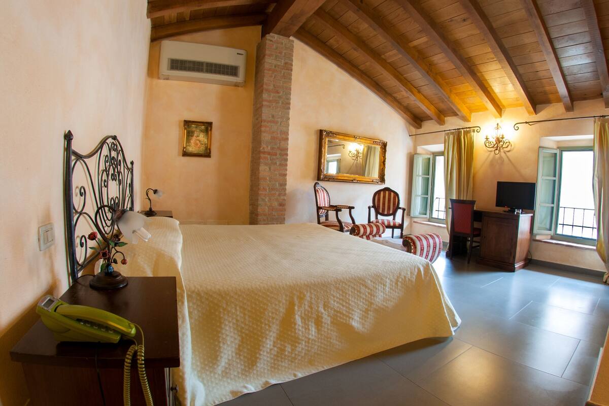 Ein Schlafzimmer mit Bett, Schreibtisch, Stuhl, Spiegel und Fenster.