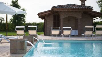 Relax by the serene pool, surrounded by lounge chairs and a shaded seating area.