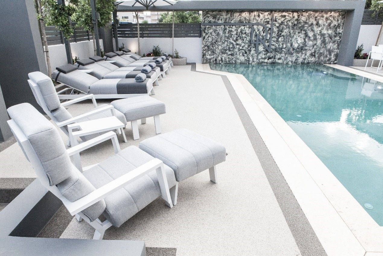 A poolside area with lounge chairs and a stone wall.