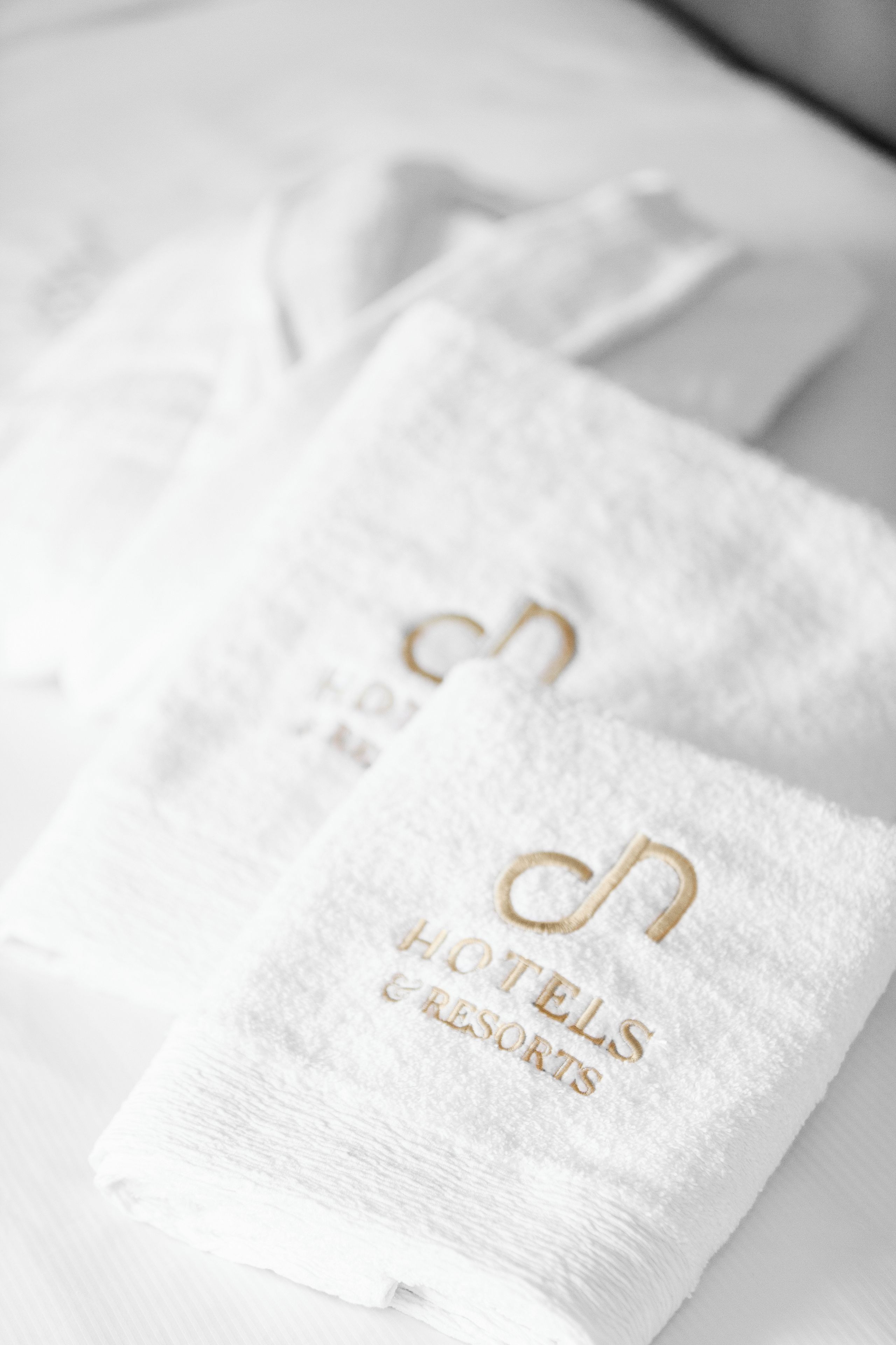 A white towel with 'HOTELS & RESORTS' embroidered in gold lettering.