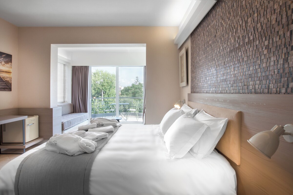 A hotel room with a bed, a desk, and a view of the outdoors.