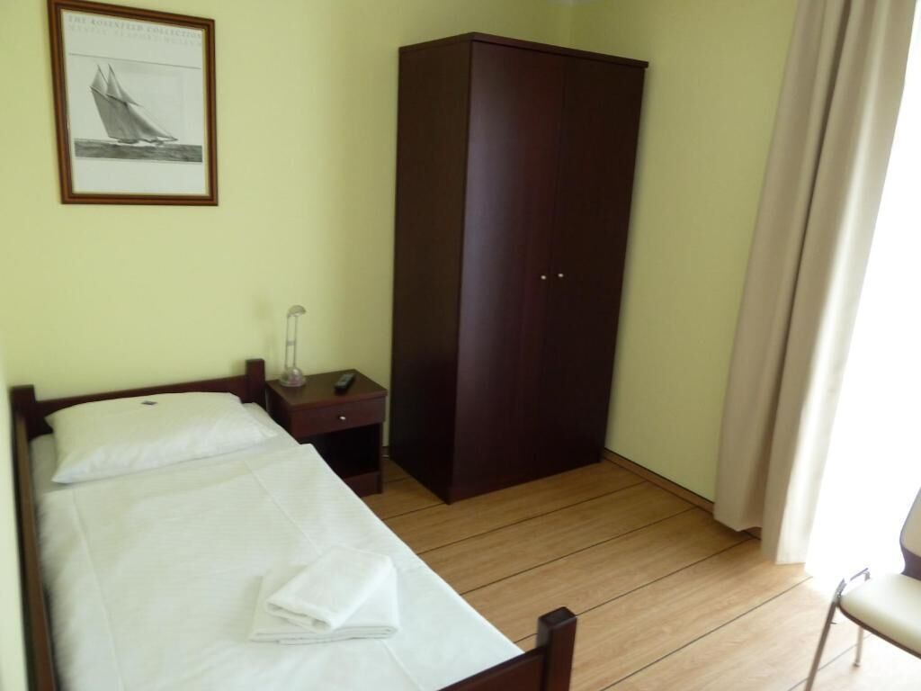 Habitació d'hotel amb llit, armari, tauleta de nit i un quadre al mur.