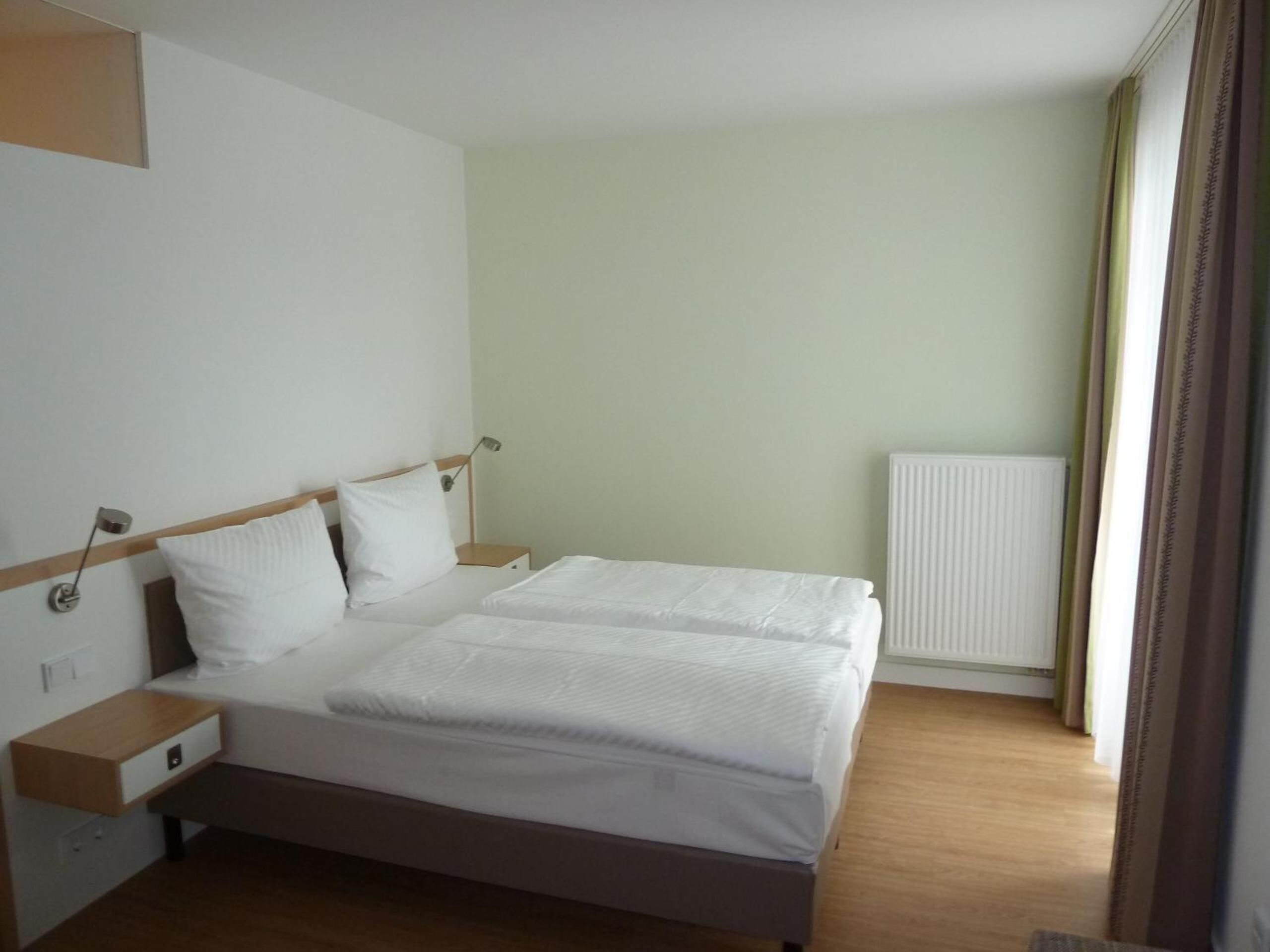 Une chambre d’hôtel avec un lit double, des tables de chevet, une lampe et un radiateur.