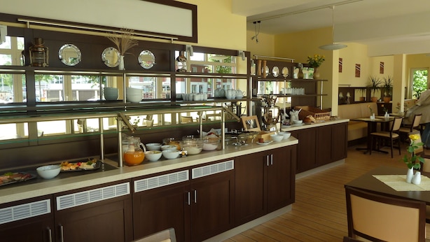 Uma cozinha espaçosa com uma ilha grande, armários de madeira e diversos utensílios de cozinha expostos em prateleiras.