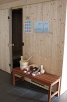 Un sauna de madera con banco, un balde de madera y un calentador.