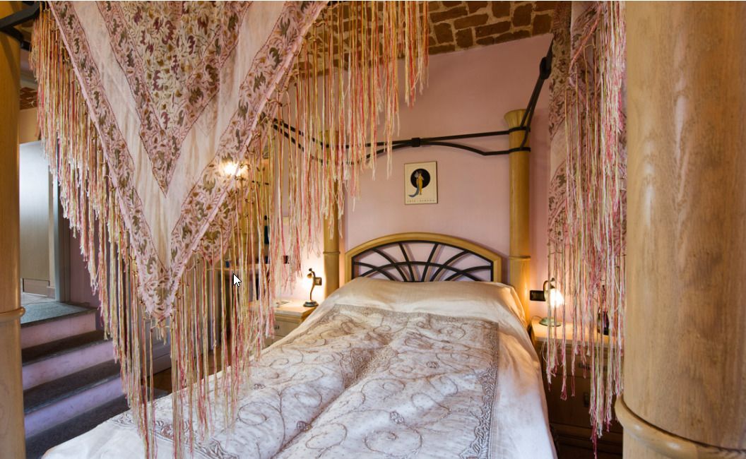 A bed with a patterned bedspread, a headboard, and a hanging canopy with tassels.