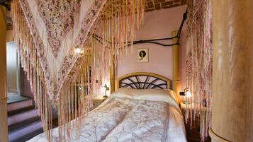 A bed with a patterned bedspread, a headboard, and a hanging canopy with tassels.