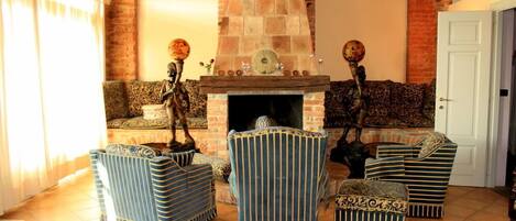 A cozy living room with a fireplace, striped armchairs, and a sofa.