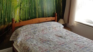 A room with a bed, a large wall mural of bamboo, and a window with curtains. - Glencoe Hotel (Bridlington)