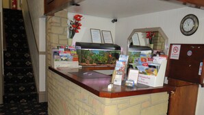 A reception desk with a fish tank, informational brochures, and a clock on the wall. - Glencoe Hotel (Bridlington)