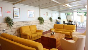 A room with yellow sofas, a wooden coffee table, and framed pictures on the walls.