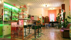 A bar area with stools, a counter, and shelves stocked with bottles.