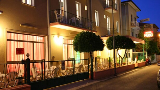A hotel with a balcony, a signboard, and a street view.