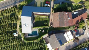 An aerial view of a residential area with a large house, a swimming pool, and a road. -  Active B&B Prairerhof (Schenna)