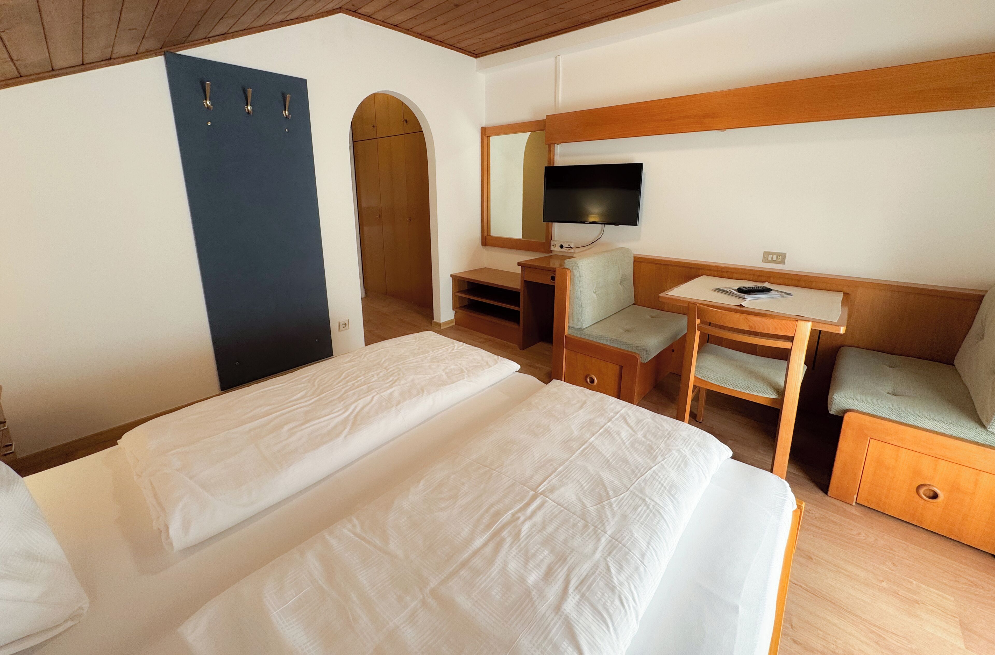 Una habitación de hotel con dos camas, un escritorio con una silla, un televisor y un armario.