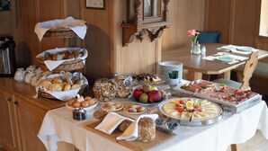 A buffet table with various food items and a clock on the wall. -  Active B&B Prairerhof (Schenna)
