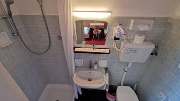Une salle de bain équipée d’une douche, de toilettes, d’un lavabo et d’un miroir.