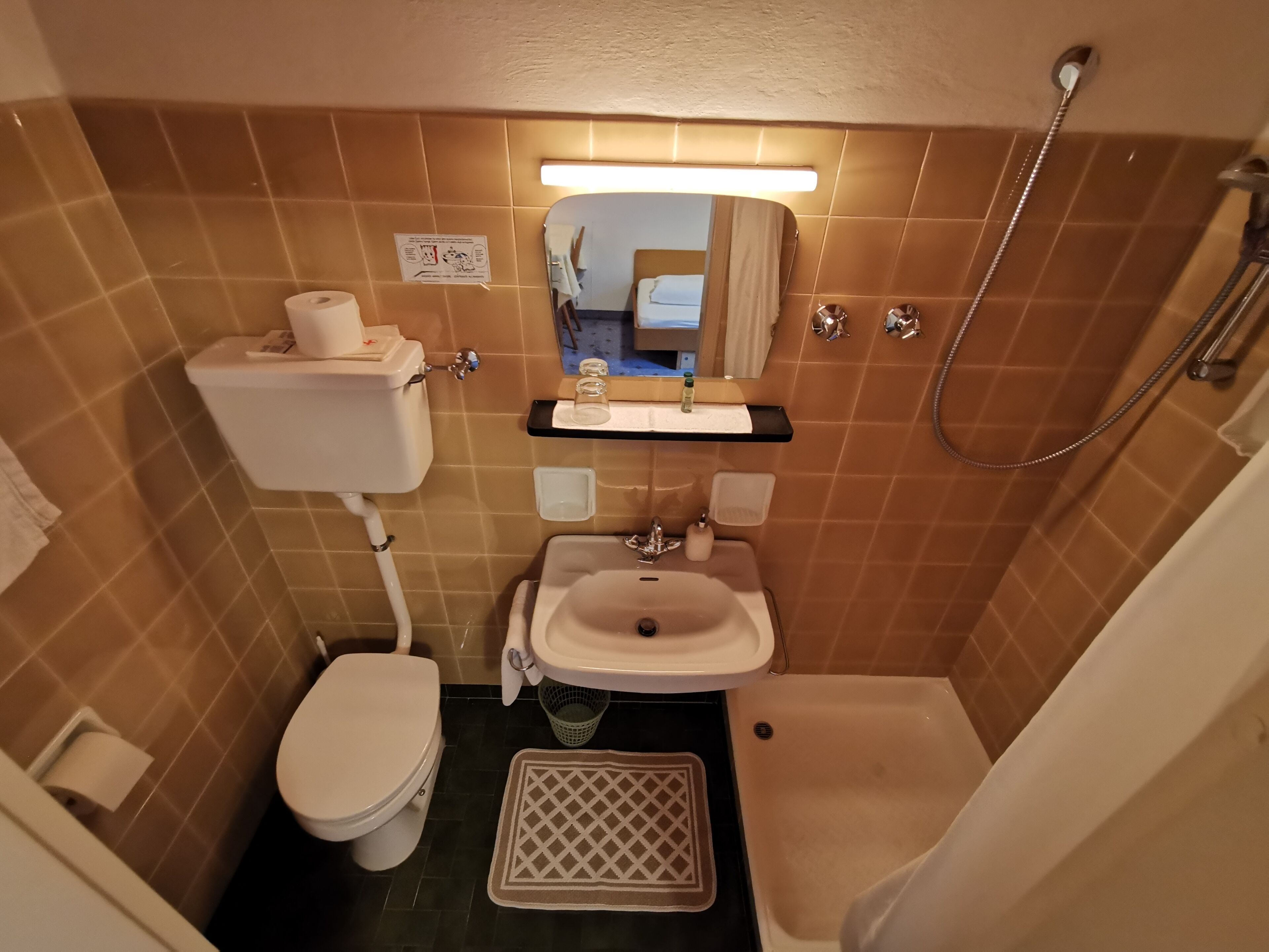 A compact bathroom with a toilet, sink, and shower.