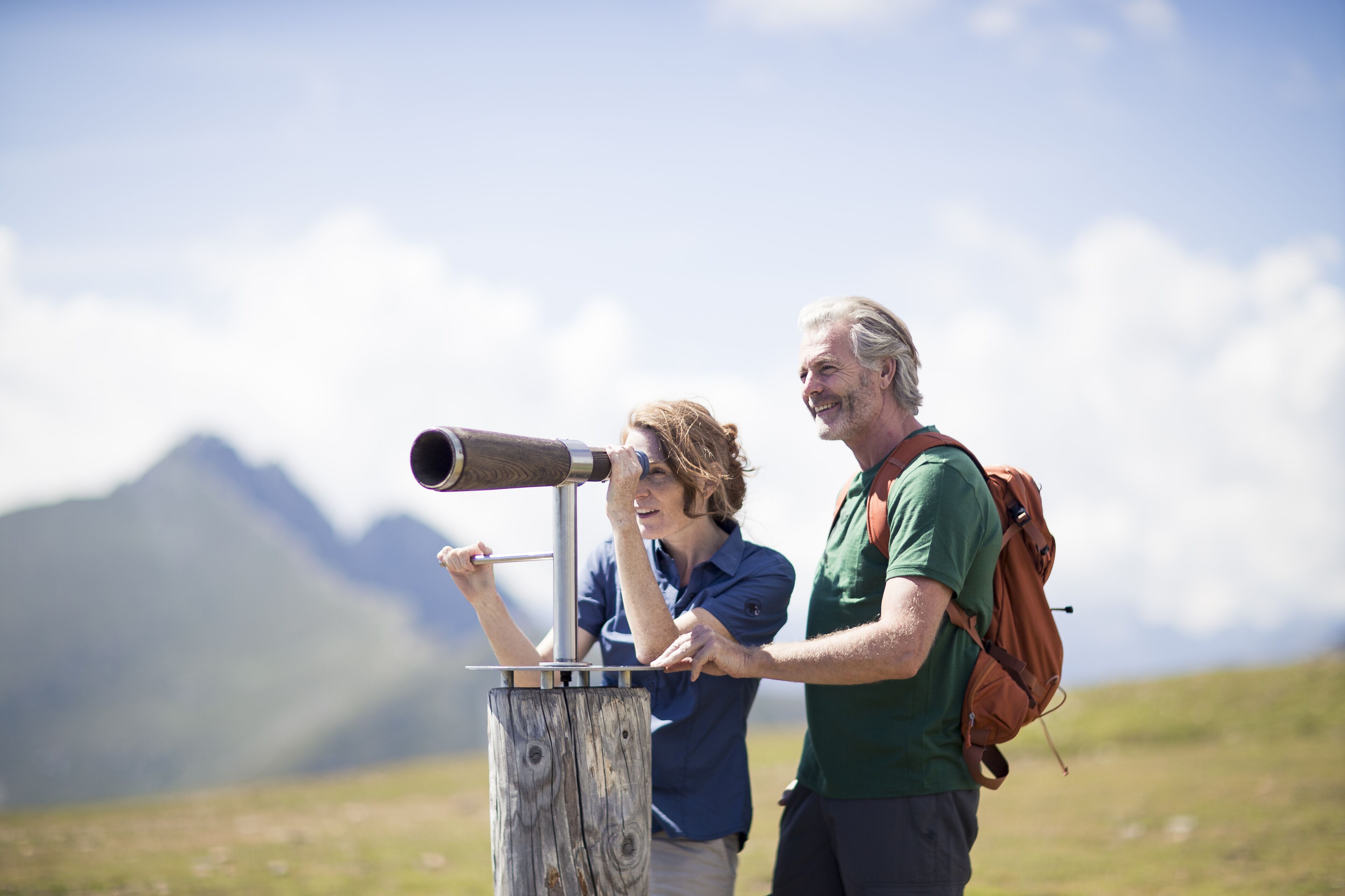 Two people using a telescope on a mountain.