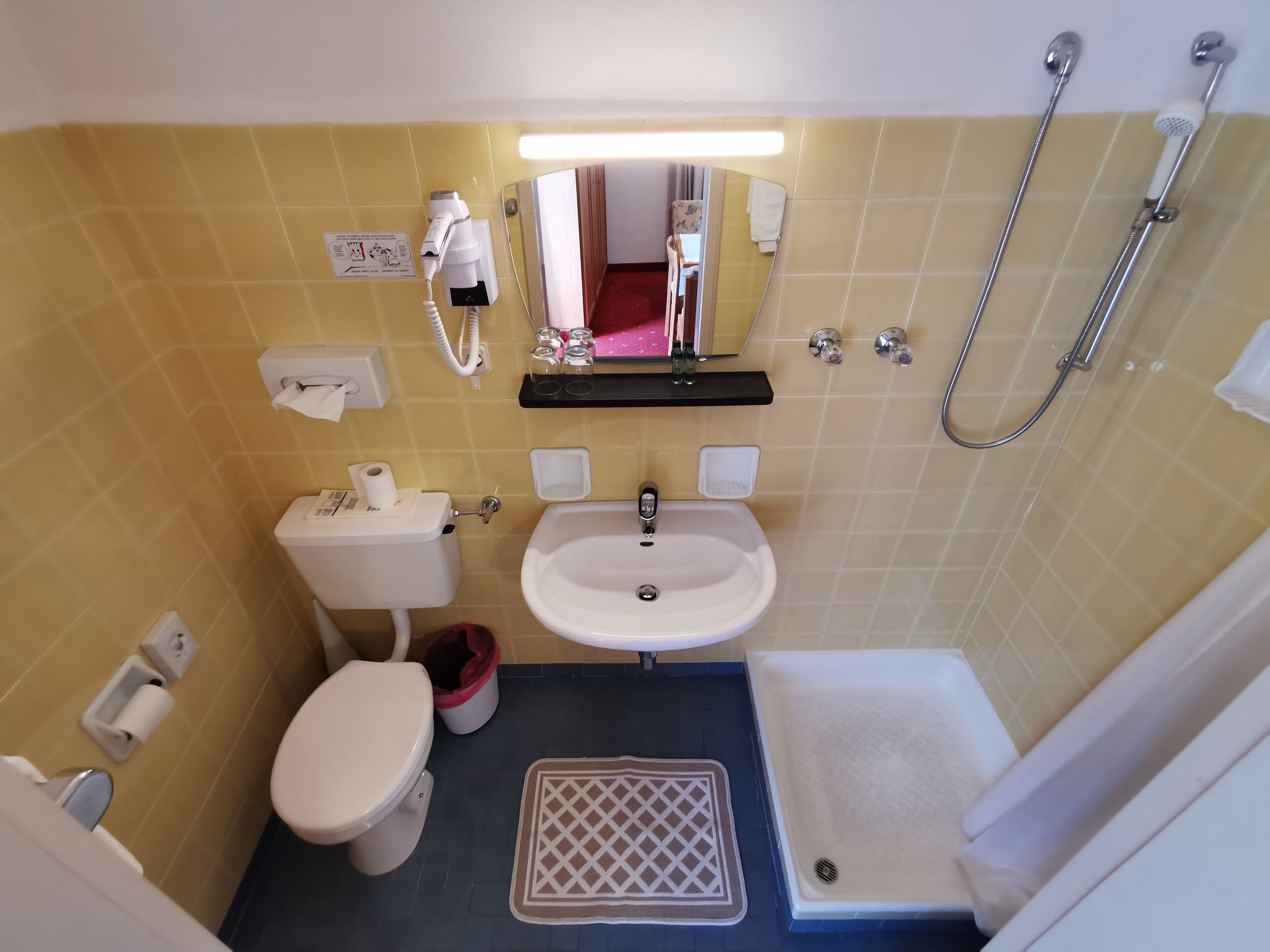 A compact bathroom with a toilet, sink, and shower.