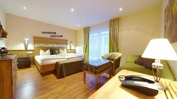 A hotel room with a bed, a desk with a telephone, a chair, a table, and a lamp.