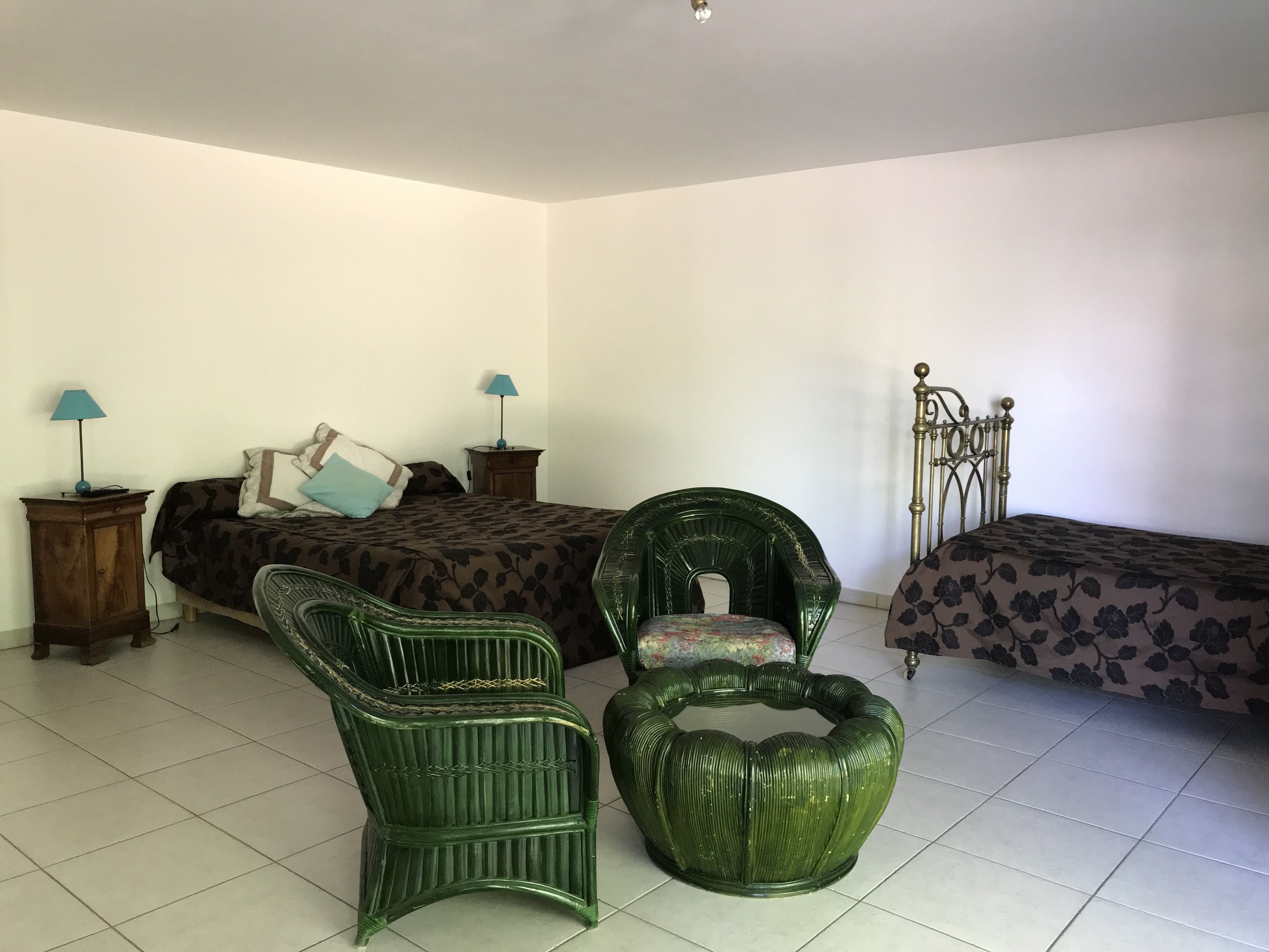 Un dormitorio con dos camas, un sillón verde, una silla verde y una estructura metálica para la cama.