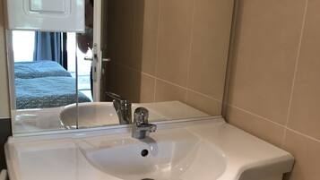 A bathroom with a white sink, a mirror, and beige tiled walls.