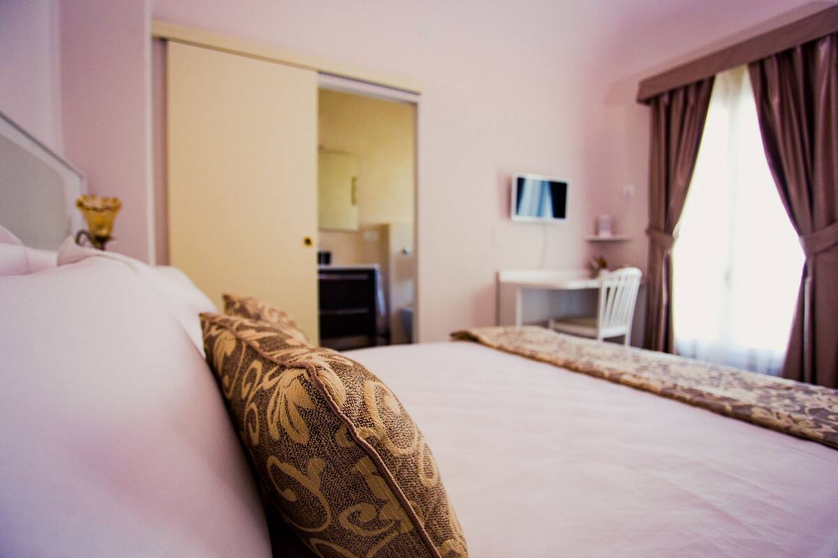 A hotel room with a bed, a desk, and a television.