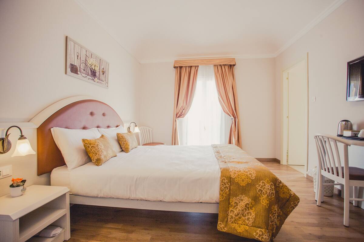 A neatly arranged hotel room with a bed, bedside table, lamp, and a chair.