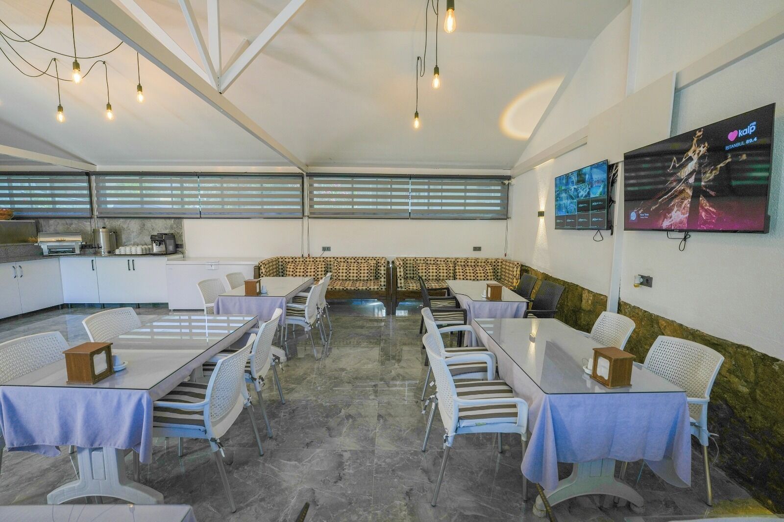 Una sala conferenze con tavoli, sedie, angolo cottura e una TV che mostra una vista sulla città.
