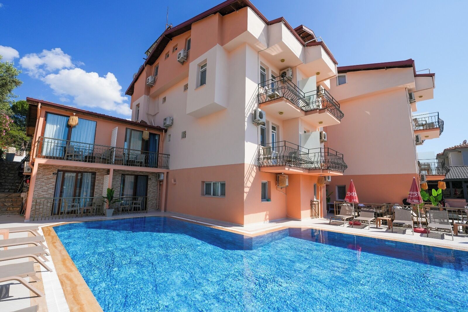Ein mehrstöckiges Hotel mit Schwimmbad, Balkonen und Außenbereich zum Sitzen.