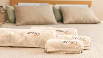 A neatly made bed with three folded towels and a wooden headboard.