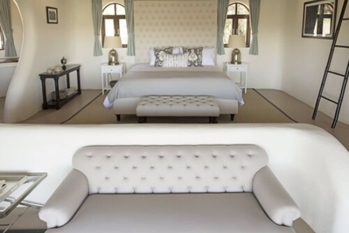 A bedroom with a large bed, a bedside table, a nightstand, and a window with curtains.