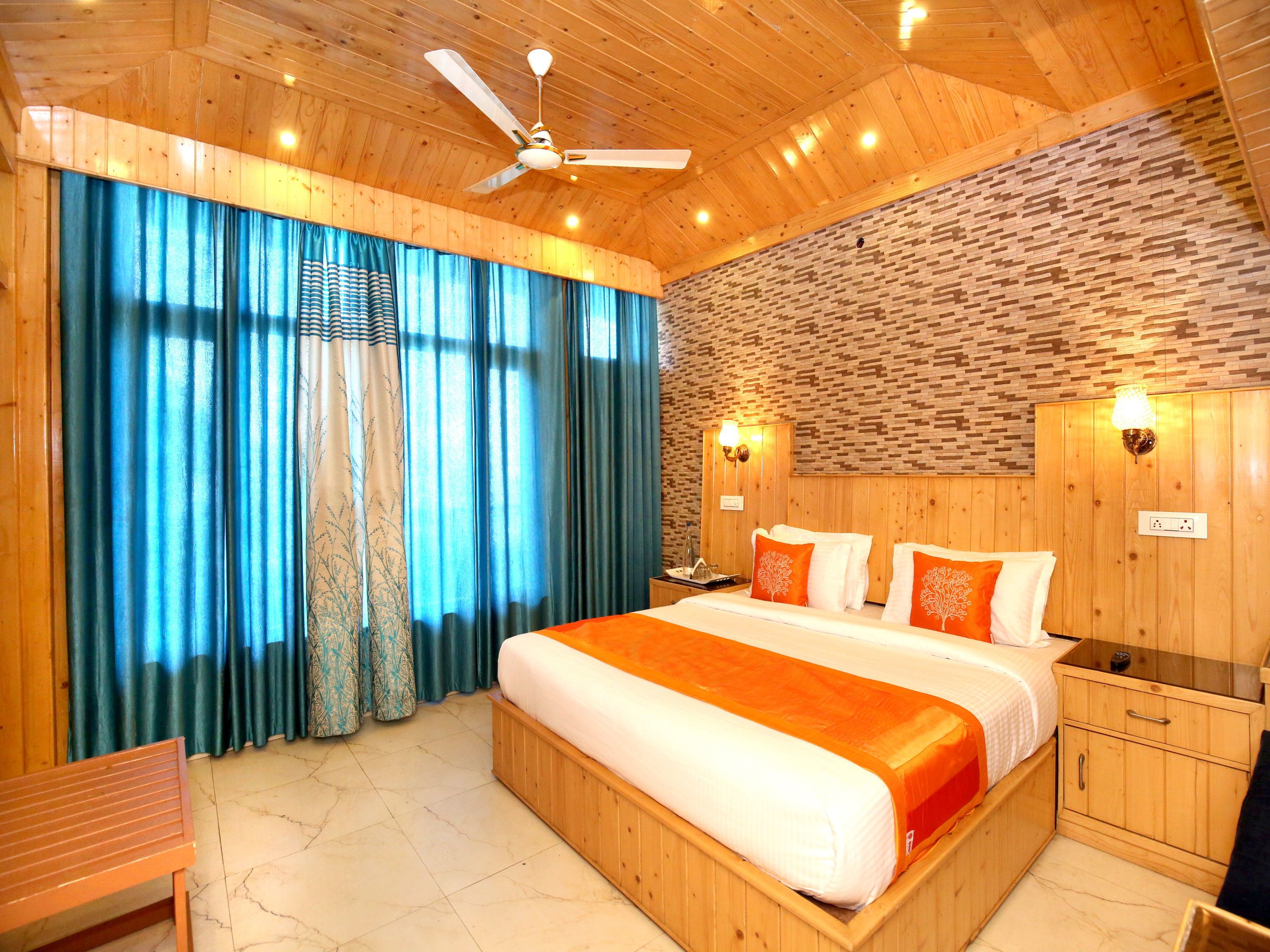 A wooden-themed bedroom with a large bed, a ceiling fan, and a stone-patterned wall.