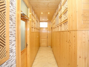 A narrow hallway with wooden walls and a tiled floor, leading to a door at the end. - OYO 12170 Home Rustic Villa Kasauli (Kasauli)