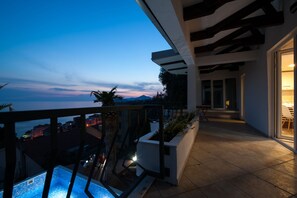 A balcony with a pool, a view of the city, and a modern architectural design.