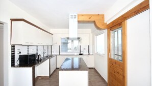 A modern kitchen with white cabinets, a central island, and a window providing natural light. - OYO 12185 Home Wayside Villa 3BHK Apartment Kasauli (Kasauli)