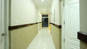 A clean, well-lit hallway with a polished floor, white walls, and a dark trim along the baseboards. - OYO 11909 Star Plaza (Aluva)