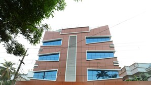 A multi-story building with a modern architectural design, featuring large windows and a central vertical element. - OYO 11909 Star Plaza (Aluva)