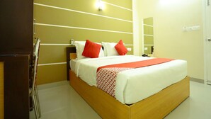 A hotel room with a wooden bed, white and red bedding, a mirror, and a wall with horizontal lines. - OYO 11909 Star Plaza (Aluva)