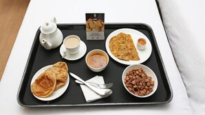 A tray with a teapot, cups, a plate of flatbread, a bowl of soup, a plate with a flatbread, a bowl of beans, and a menu. - OYO 11909 Star Plaza (Aluva)