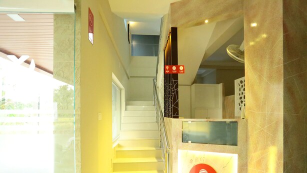 A staircase leading to a reception area with a sign indicating the operating hours. - OYO 11909 Star Plaza (Aluva)