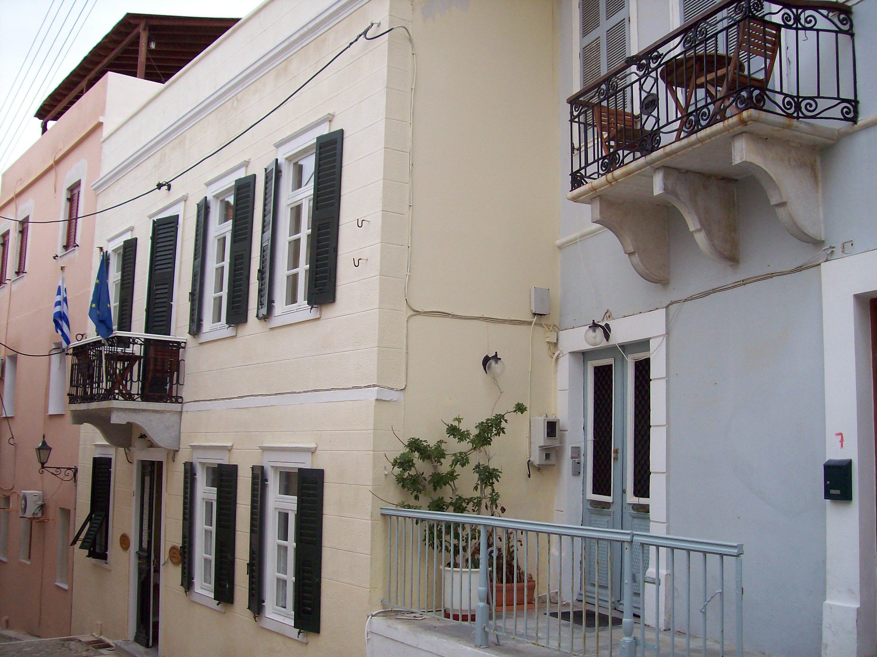 A row of buildings with balconies, shutters, and a flag.