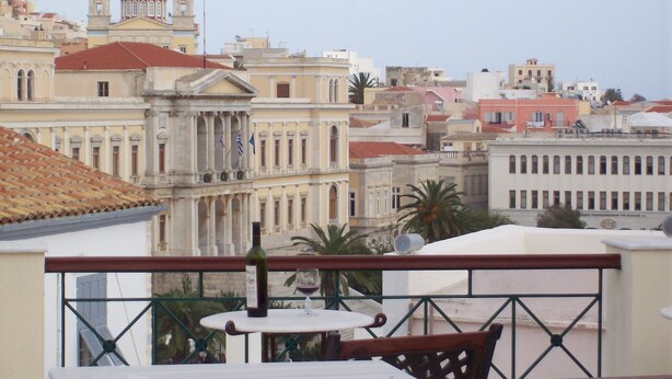 A terrace with a table and chairs, overlooking a cityscape with historic buildings and a prominent church with a blue dome.