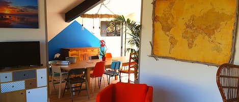 Una sala moderna con comedor, un gran mapa del mundo en la pared y un televisor sobre un mueble de madera.