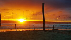 Um pôr do sol sobre o oceano, com uma cerca de arame ao primeiro plano.