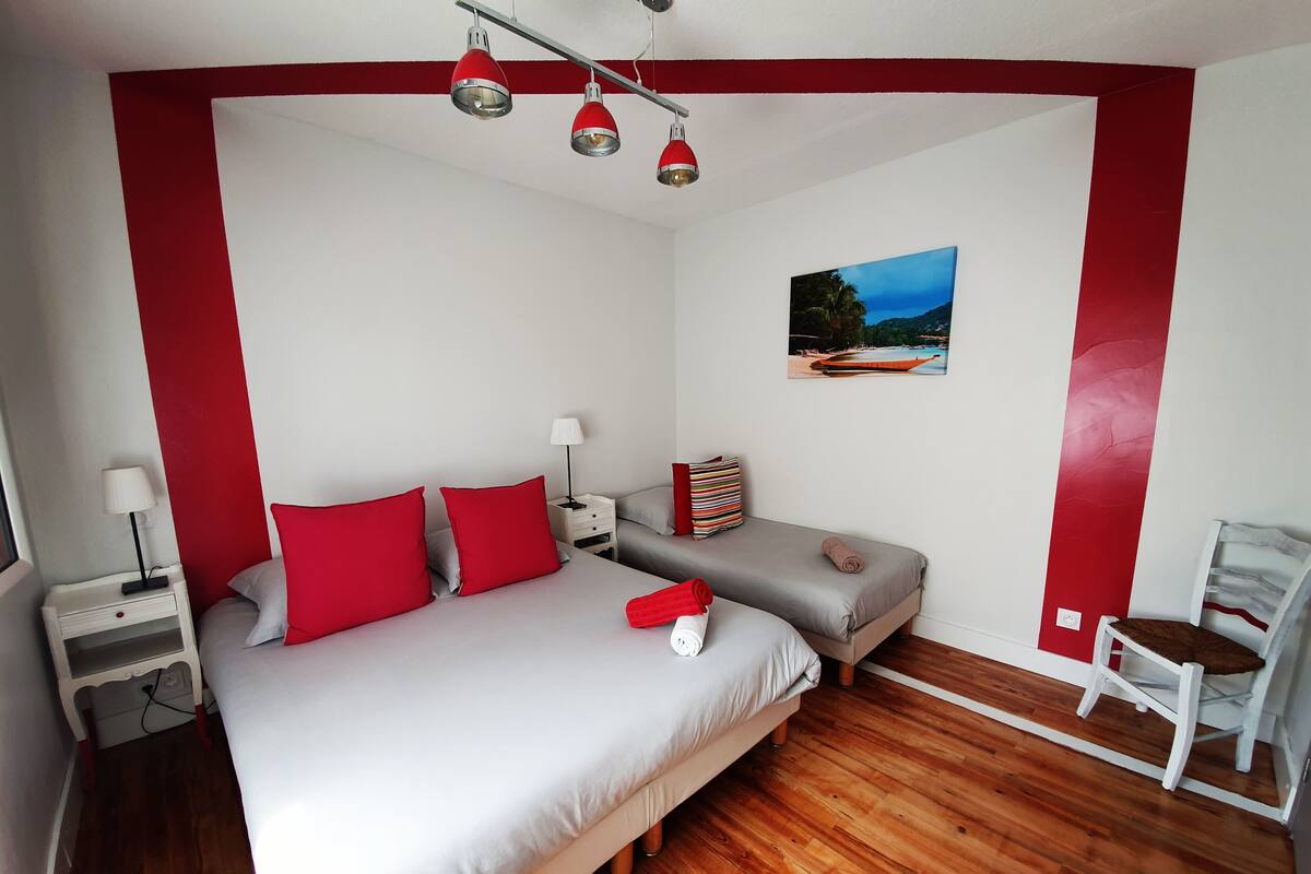 Un dormitorio con una cama, dos mesitas de noche, una silla y un cuadro en la pared.